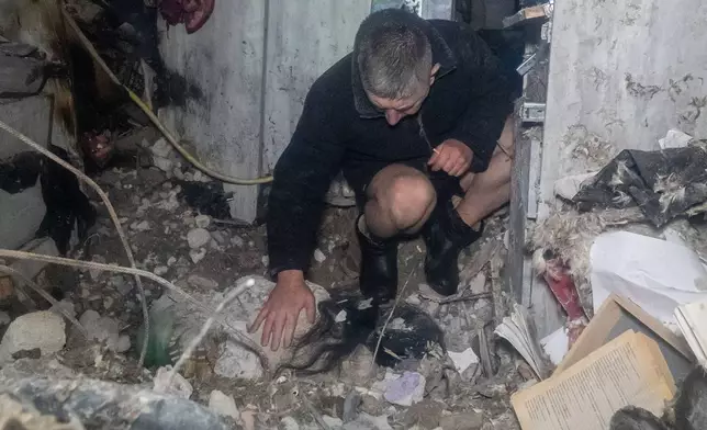 A man reacts at the dead body his wife after his residential building was damaged by a Russian attack in Kharkiv, Ukraine, late Sunday, Nov. 23, 2025. (AP Photo/Andrii Marienko)