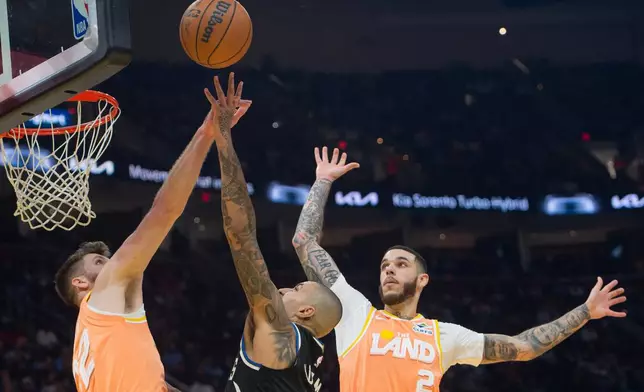 Milwaukee Bucks' Kyle Kuzma, center, shoots over Cleveland Cavaliers' Dean Wade, left, and Lonzo Ball (2) during the first half of an NBA basketball game in Cleveland, Monday, Nov. 17, 2025. (AP Photo/Phil Long)