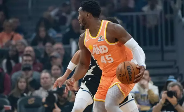 Cleveland Cavaliers' Donovan Mitchell (45) looks to pass as Milwaukee Bucks' Ryan Rollins, rear, obscured, defends during the first half of an NBA basketball game in Cleveland, Monday, Nov. 17, 2025. (AP Photo/Phil Long)