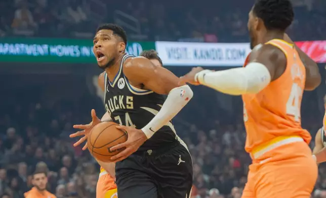 Milwaukee Bucks' Giannis Antetokounmpo drives to the basket as Cleveland Cavaliers' Donovan Mitchell, right, looks on during the first half of an NBA basketball game in Cleveland, Monday, Nov. 17, 2025. (AP Photo/Phil Long)