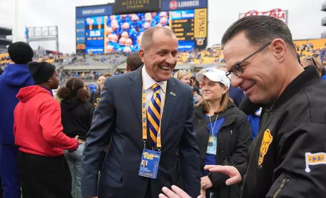 ACC Commissioner Jim Phillips, center, visits with Pennsylvania Governor Josh Shapiro, right, on the field before an NCAA college football game between Pittsburgh and Notre Dame in Pittsburgh, Nov. 15, 2025. (AP Photo/Gene J. Puskar)