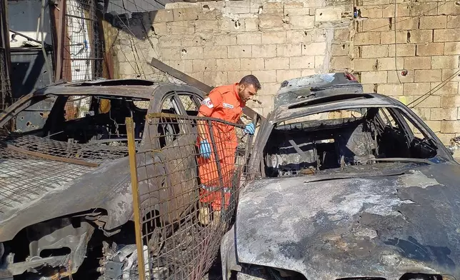 A Palestinian rescue worker checks cars that were damaged in an Israeli strike on Tuesday night at the Ein el-Hilweh Palestinian refugee camp, in the southern port city of Sidon, Lebanon, Wednesday, Nov. 19, 2025. (AP Photo/Mohammed Zaatari)