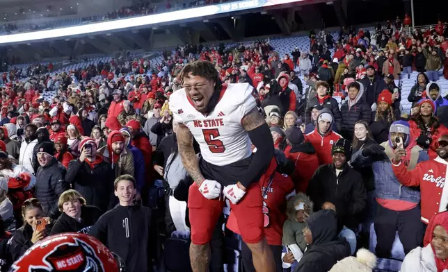 FILE -North Carolina State safety DK Kaufman (5) celebrates with the fans after defeating rival North Carolina in an NCAA college football game, Nov. 30, 2024, in Chapel Hill, N.C. (AP Photo/Chris Seward, File)