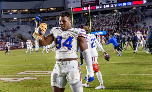 FILE -Florida edge Tyreak Sapp (94) holds a manikin head decorated like the Florida State mascot at midfield after his team defeated Florida State 31-11 in an NCAA college football game, Nov. 30, 2024, in Tallahassee, Fla. (AP Photo/Colin Hackley, File)