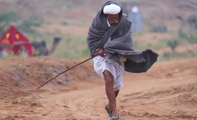 Narma Ram, a camel herder, walks towards his temporary tent as it drizzle at the annual Pushkar cattle fair, in the western Indian state of Rajasthan, Monday, Oct. 27, 2025. (AP Photo/Rajesh Kumar Singh)