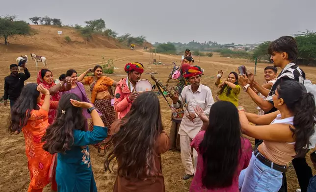 Tourists dance with locals during the annual cattle fair in Pushkar, in the western Indian state of Rajasthan, Monday, Oct. 27, 2025. (AP Photo/Rajesh Kumar Singh)