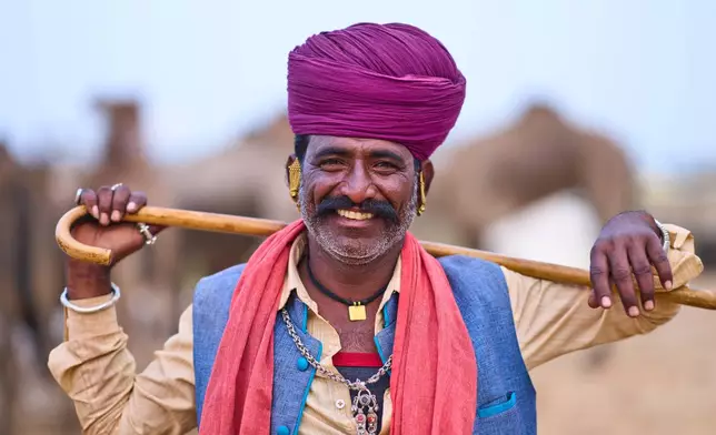 A camel herder poses for a photograph at the annual cattle fair in Pushkar, in the western Indian state of Rajasthan, Sunday, Oct. 26, 2025. (AP Photo/Rajesh Kumar Singh)