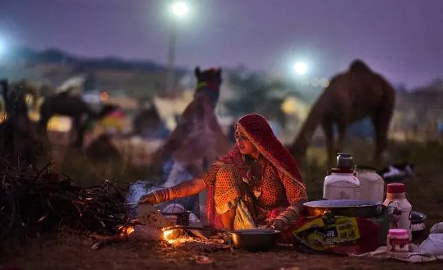 A woman prepares food at the annual cattle fair in Pushkar, in the western Indian state of Rajasthan, Sunday, Oct. 26, 2025. (AP Photo/Rajesh Kumar Singh)