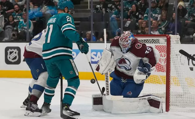 Colorado Avalanche goaltender Mackenzie Blackwood, right, defends against a shot next to San Jose Sharks center Alexander Wennberg (21) during the first period of an NHL hockey game in San Jose, Calif., Saturday, Nov. 1, 2025. (AP Photo/Jeff Chiu)