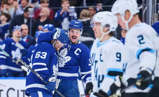 Toronto Maple Leafs' Auston Matthews (34) celebrates with teammate Matias Maccelli (63) after scoring against the Utah Mammothsduring second period NHL hockey action in Toronto, on Wednesday, Nov. 5, 2025. (Sammy Kogan/The Canadian Press via AP)