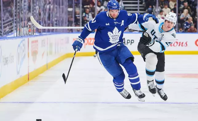 Toronto Maple Leafs' John Tavares (91) and Utah Mammoth's Dmitri Simashev (26) battle for the puck during second period NHL hockey action in Toronto, on Wednesday, Nov. 5, 2025. (Sammy Kogan/The Canadian Press via AP)