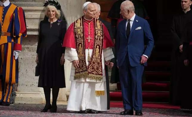 FILE - Pope Leo XIV, center, is flanked by Britain's King Charles III and Queen Camilla in the St. Damasus Courtyard at the Vatican after a state visit and a pray with him in the Sistine Chapel, Oct. 23, 2025. (AP Photo/Andrew Medichini, File )