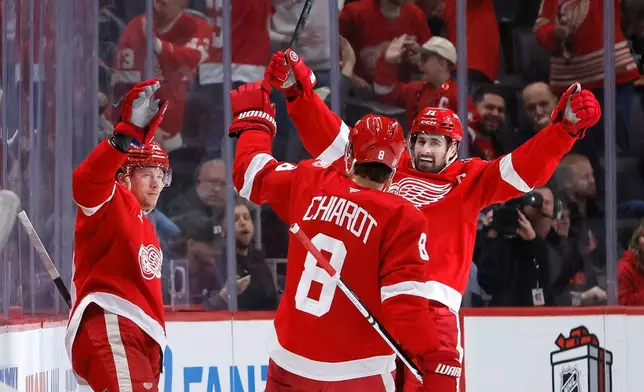 Detroit Red Wings left wing Lucas Raymond, left, celebrates with defenseman Ben Chiarot (8) and center Dylan Larkin, right, after scoring a goal against the Columbus Blue Jackets during the second period of an NHL hockey game Saturday, Nov. 22, 2025, in Detroit. (AP Photo/Duane Burleson)