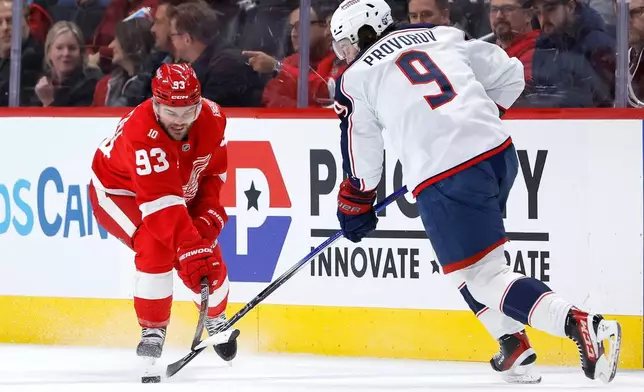 Detroit Red Wings right wing Alex Debrincat (93) tries to steal the puck from Columbus Blue Jackets defenseman Ivan Provorov (9) during the first period of an NHL hockey game Saturday, Nov. 22, 2025, in Detroit. (AP Photo/Duane Burleson)