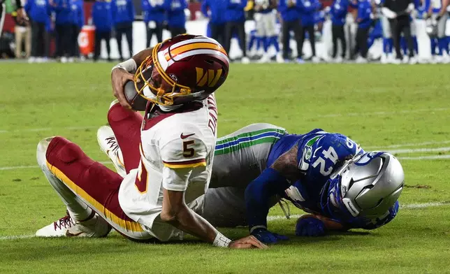 Washington Commanders quarterback Jayden Daniels (5) injures his arm as he is tackled by Seattle Seahawks linebacker Drake Thomas (42) during the second half of an NFL football game, Sunday, Nov. 2, 2025, in Landover, Md. (AP Photo/Nick Wass)