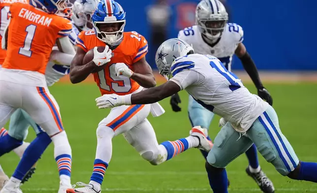 Denver Broncos wide receiver Marvin Mims Jr. (19) attempts to get past Dallas Cowboys safety Markquese Bell (14) in the second half of an NFL football game Sunday, Oct. 26, 2025, in Denver. (AP Photo/David Zalubowski)