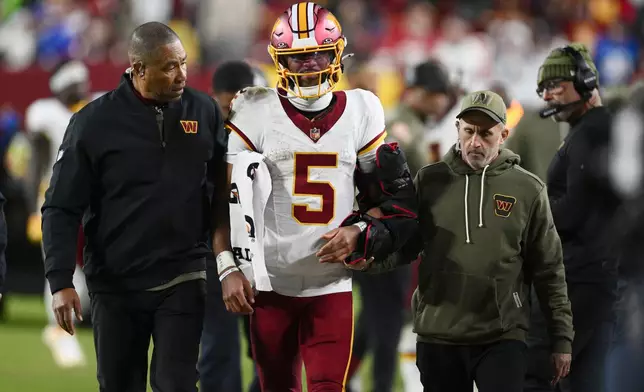 Washington Commanders quarterback Jayden Daniels (5) is helped off the field after injuring his arm in the second half of an NFL football game against the Seattle Seahawks, Sunday, Nov. 2, 2025, in Landover, Md. (AP Photo/Nick Wass)