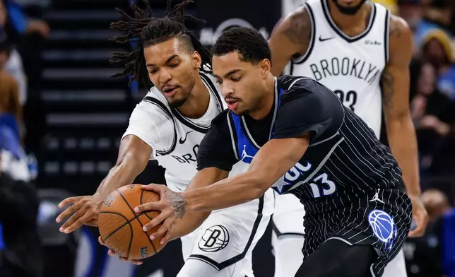 Orlando Magic guard Jett Howard, right, and Brooklyn Nets forward Ziaire Williams, left, go after a loose ball during the first half of an NBA Cup basketball game Friday, Nov. 14, 2025, in Orlando, Fla. (AP Photo/Kevin Kolczynski)