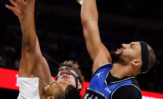Orlando Magic guard Jalen Suggs, right, and Magic forward Franz Wagner, center, stop Brooklyn Nets forward Ziaire Williams, left, lay-up during the first half of an NBA Cup basketball game, Friday, Nov. 14, 2025, in Orlando, Fla. (AP Photo/Kevin Kolczynski)