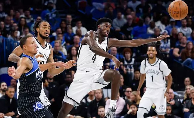 Orlando Magic guard Desmond Bane, left, has pass blocked by Brooklyn Nets guard Drake Powell (4) and team mate Nets center Nic Claxton, center, during the first half of an NBA Cup basketball game, Friday, Nov. 14, 2025, in Orlando, Fla. (AP Photo/Kevin Kolczynski)