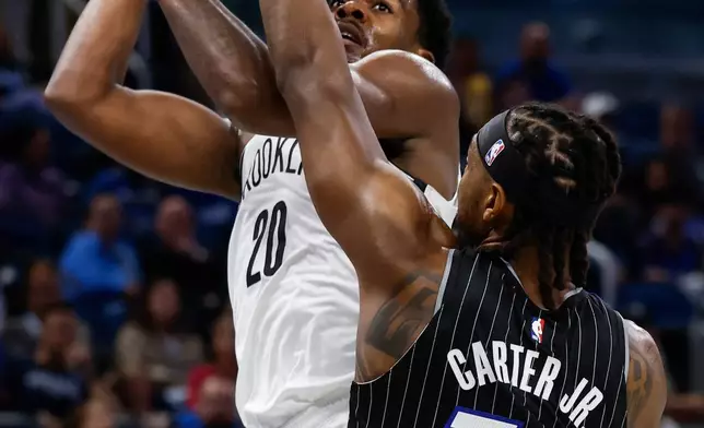 Brooklyn Nets center Day'Ron Sharpe (20) shoots over Orlando Magic center Wendell Carter Jr. (34) during the first half of an NBA Cup basketball game Friday, Nov. 14, 2025, in Orlando, Fla. (AP Photo/Kevin Kolczynski)