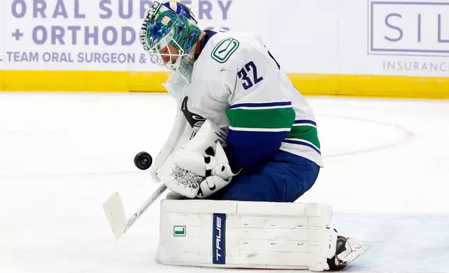 Vancouver Canucks goaltender Kevin Lankinen (32) blocks a shot of the Carolina Hurricanes during the second period of an NHL hockey game in Raleigh, N.C., Friday, Nov. 14, 2025. (AP Photo/Karl DeBlaker)