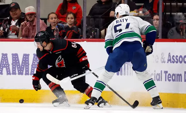 Carolina Hurricanes' Joel Nystrom (64) and Aatu Raty (54) battle for the puck during the second period of an NHL hockey game in Raleigh, N.C., Friday, Nov. 14, 2025. (AP Photo/Karl DeBlaker)