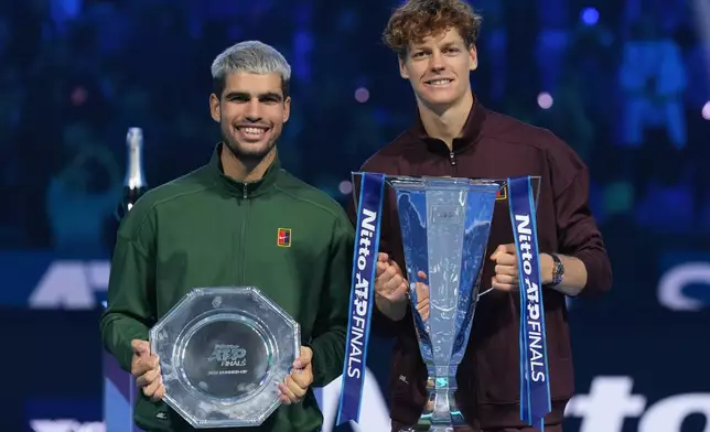 Spain's Carlos Alcaraz, left, and winner Italy's Jannik Sinner stand on the podium after the final tennis match of the ATP World Tour Finals, in Turin, Italy, Sunday, Nov. 16, 2025. (AP Photo/Antonio Calanni)