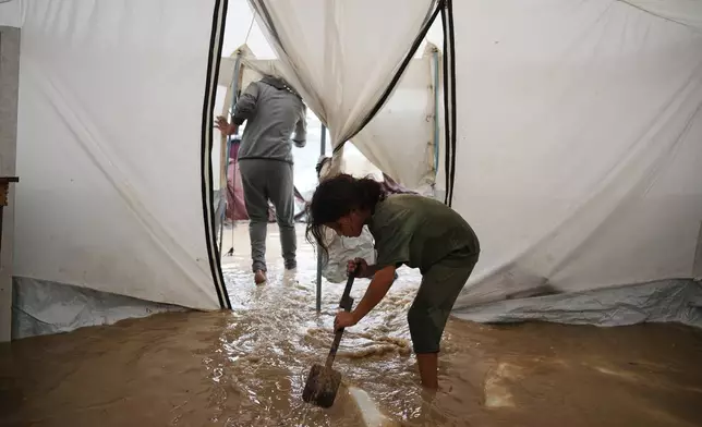 Saja Fayyad, 7, tries to clear water from her family's flooded tent at a temporary camp for displaced Palestinians after heavy rainfall in Deir al-Balah, central Gaza Strip, Tuesday, Nov. 25, 2025. (AP Photo/Abdel Kareem Hana)