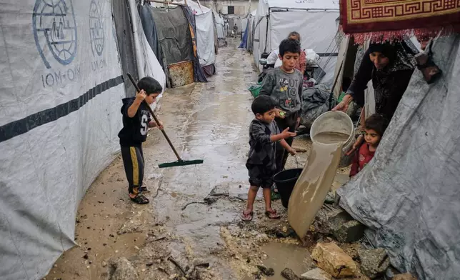 Displaced Palestinians clear water from their flooded tent at a temporary camp after heavy rainfall in Gaza City Tuesday, Nov. 25, 2025. (AP Photo/Jehad Alshrafi)