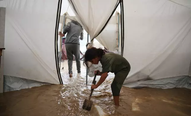 Saja Fayyad, 7, tries to clear water from her family's flooded tent at a temporary camp for displaced Palestinians after heavy rainfall in Deir al-Balah, central Gaza Strip, Tuesday, Nov. 25, 2025. (AP Photo/Abdel Kareem Hana)