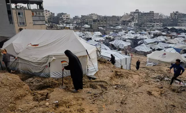 Displaced Palestinians walk through mud at a temporary tent camp following heavy rainfall in Gaza City on Tuesday, Nov. 25, 2025. (AP Photo/Jehad Alshrafi)