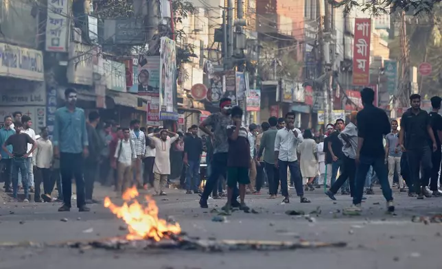 Protesters throw stones and shout slogans during a standoff with police outside the demolished residence of Sheikh Mujibur Rahman, Bangladesh's former leader and the father of the country's ousted Prime Minister Sheikh Hasina following the verdict against her, in Dhaka, Bangladesh, Monday, Nov. 17, 2025. (AP Photo/ Rajib Dhar)
