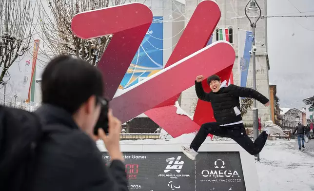 South Korean skeleton athlete Jung Seunggi, right, has a photo taken in front of the Milan Cortina Winter Olympics countdown clock, in Cortina D'Ampezzo, Thursday, Nov. 20, 2025. (AP Photo/Andrew Medichini)