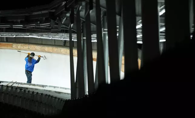 A man works on the track ahead of a three-day skeleton and bobsled World Cup stage and Olympic test event in Cortina D'Ampezzo, Italy, Wednesday, Nov. 19, 2025. (AP Photo/Andrew Medichini)