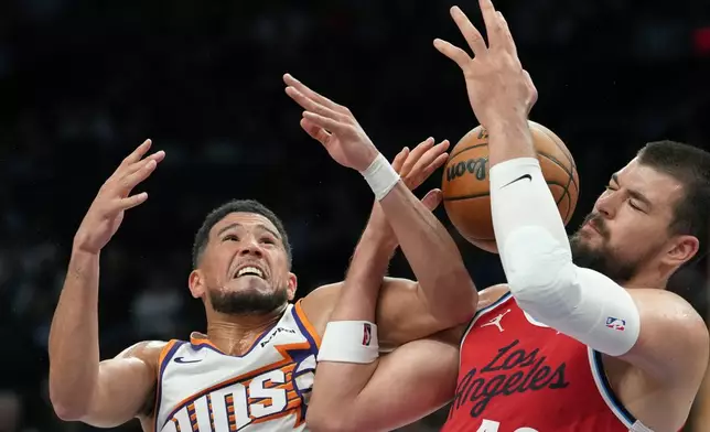 Phoenix Suns guard Devin Booker, left, fouls Los Angeles Clippers center Ivica Zubac as they battle for a rebound during the first half of an NBA basketball game Thursday, Nov. 6, 2025, in Phoenix. (AP Photo/Ross D. Franklin)