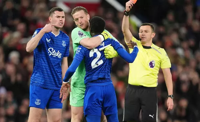 Everton's Idrissa Gueye, second right, is held back by teammate Jordan Pickford as he argues with Michael Keane, left, after getting a red card from referee Tony Harrington during the English Premier League soccer match between Manchester United and Everton in Manchester, England, Monday, Nov. 24, 2025. (Martin Rickett/PA via AP)