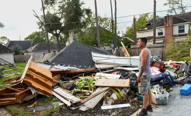 Jose Rosas surveys damage to Guillermo Vargas' home as while helping clean up storm damage in the Memorial Northwest subdivision, in Spring, Texas, Monday, Nov. 24, 2025. (Brett Coomer/Houston Chronicle via AP)