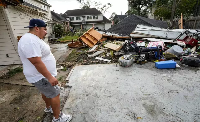 Guillermo Vargas surveys damage to his home, where his garage was swept off its foundation, while cleaning up storm damage after severe weather hit in the Memorial Northwest subdivision, in Spring, Texas, Monday, Nov. 24, 2025. (Brett Coomer/Houston Chronicle via AP)
