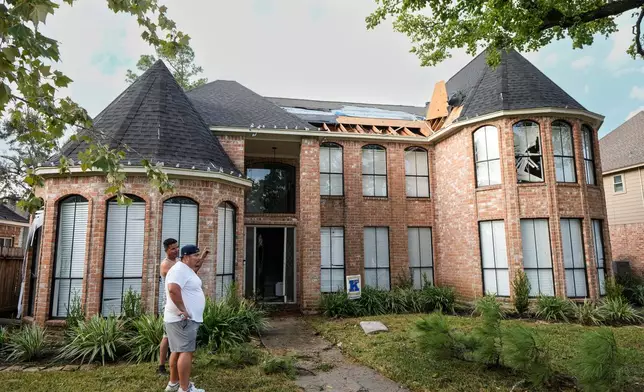 Jose Rosas, left, and Guillermo Vargas survey damage to Vargas' home as they clean up storm damage in the Memorial Northwest subdivision in Spring, Texas, Monday, Nov. 24, 2025. (Brett Coomer/Houston Chronicle via AP)