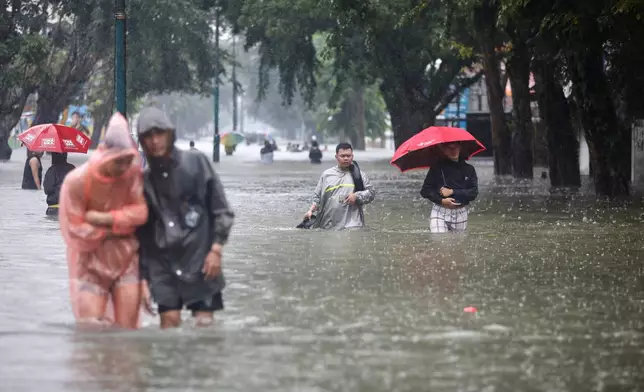 People wade through the water at a flooded street in Medan, North Sumatra, Indonesia, Thursday, Nov. 27, 2025. (AP Photo/Binsar Bakkara)
