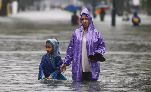 People wade through the water at a flooded street in Medan, North Sumatra, Indonesia, Thursday, Nov. 27, 2025. (AP Photo/Binsar Bakkara)