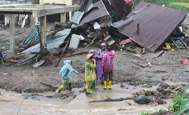 Residents inspect houses damaged during a flood in Malalak, West Sumatra, Indonesia, Thursday, Nov. 27, 2025. (AP Photo/Ade Yuandha)