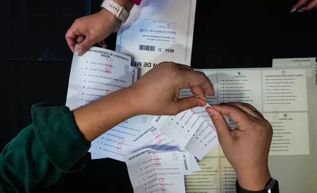 An electoral worker prepares demonstration ballots inside the old Mapocho train station that is now a cultural center to be used as a polling station for the general election in Santiago, Chile, Friday, Nov. 14, 2025. (AP Photo/Esteban Felix)