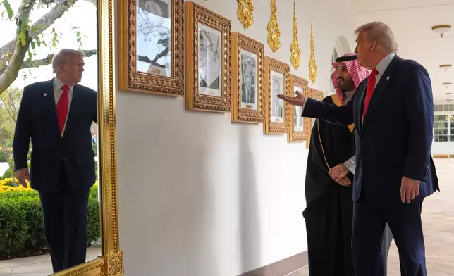 President Donald Trump shows Saudi Arabia's Crown Prince Mohammed bin Salman portraits of former president as they walk along the Colonnade at the White House, Tuesday, Nov. 18, 2025, in Washington. (AP Photo/Evan Vucci)