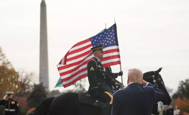 President Donald Trump salutes as a solider on horseback passes with an American flag as he waits to welcome Saudi Arabia's Crown Prince Mohammed bin Salman to the White House, Tuesday, Nov. 18, 2025, in Washington. (AP Photo/Evan Vucci)