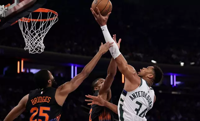 Milwaukee Bucks forward Giannis Antetokounmpo, right, drives to the basket against New York Knicks guard Mikal Bridges (25) during the first half of an NBA basketball game, Friday, Nov. 28, 2025, in New York. (AP Photo/Adam Hunger)