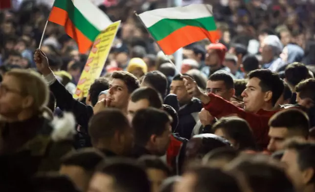 Protesters whistle and wave Bulgarian flags as thousands took to the streets of Bulgaria's capital, Sofia, to denounce steep tax hikes in next year's draft budget before being finally voted on in parliament, Wednesday, Nov 26, 2025. (AP Photo/Valentina Petrova)