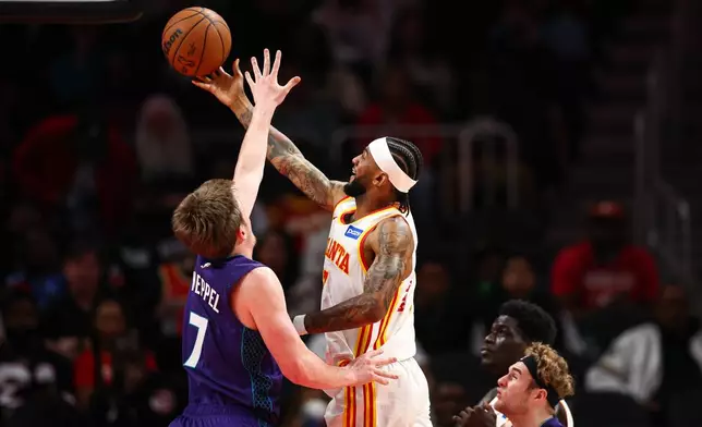Atlanta Hawks guard Nickeil Alexander-Walker, center, shoots against Charlotte Hornets guard Kon Knueppel (7) during the first half of an NBA basketball game, Sunday, Nov. 23, 2025, in Atlanta. (AP Photo/Colin Hubbard)
