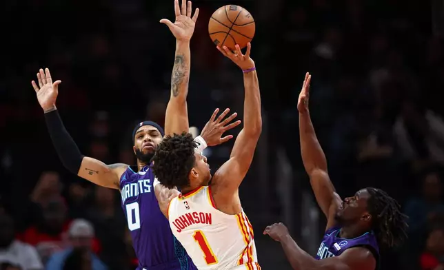 Atlanta Hawks forward Jalen Johnson (1) shoots against Charlotte Hornets forward Miles Bridges (0) and guard Sion James, right, during the first half of an NBA basketball game, Sunday, Nov. 23, 2025, in Atlanta. (AP Photo/Colin Hubbard)